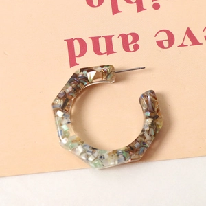 Macro detail of C-shaped resin earring featuring colorful embedded shell fragments