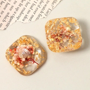 Macro shot of resin jewelry parts with gold foil, pink dried flowers and small shells