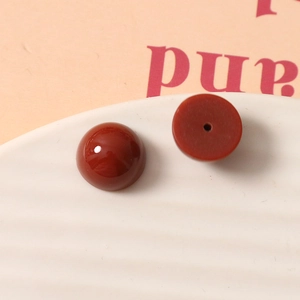 Détail macro de perles demi-rondes en résine rouge brique 12mm avec surface lisse et trou central