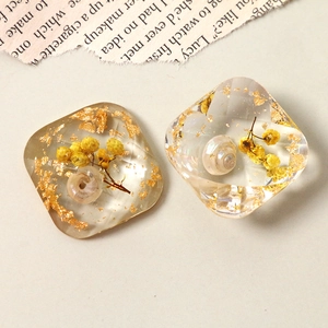 Detailed macro view of resin charms with gold foil, dried flowers and tiny seashells