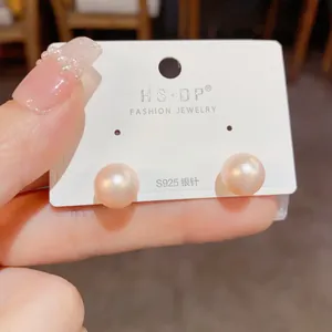 Detailed shot of round pink pearl earrings with s925 silver posts on display card