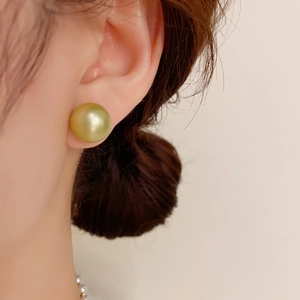 Close-up of golden pearl earring with high mirror luster on model for elegant styling