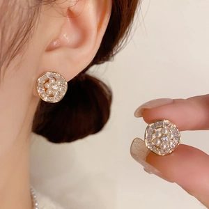 Pendientes de oro con perlas y circonitas de estilo francés mostrados en una modelo