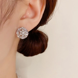 Elegantes pendientes de flores con perlas y circonitas usados por una modelo