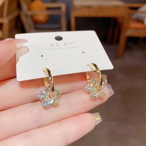 Macro shot of gold floral earrings with crystal-encrusted petals on a jewelry card