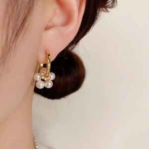 Elegant gold flower earrings with white pearls and crystals worn on model's ear