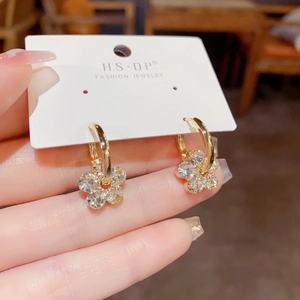 Macro detail of gold flower hoop earrings with clear crystals on a display card