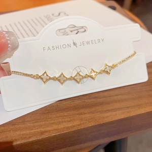 Detail of adjustable gold star bracelet with white shell inlays on display card