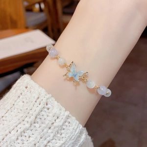Detail of elegant butterfly pendant bracelet with opal beads on a female wrist