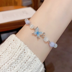 Close-up of light blue butterfly charm bracelet with lavender beads and cat eye stones
