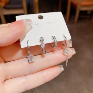 Close-up of four silver earrings featuring cubic zirconia in various geometric shapes