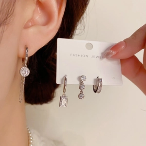 Detail of silver earrings set featuring long tassel drop and square zircon charms