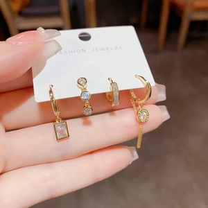 Detail view of four-piece gold earring set with rectangle zircon and chain drops