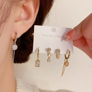 Detail of five asymmetric gold and silver earrings set with cubic zirconia stones