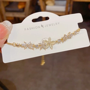 Close-up of a gold flower bracelet featuring cat eye stones and sparkling zircon details