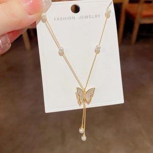 Elegant gold butterfly tassel necklace with mother of pearl and pearls on a white card