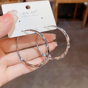 Boucles d'oreilles créoles torsadées argentées avec tiges en argent S925 sur une carte