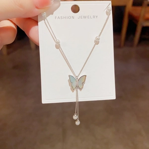 Macro detail of silver butterfly necklace with iridescent wings and small white pearls