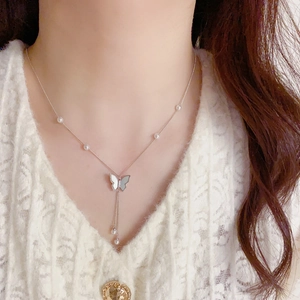 Detail of butterfly shell pendant necklace with white pearls and long tassel fringes