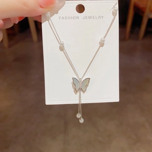 Elegant silver butterfly tassel necklace with pearl accents and shell texture pendant