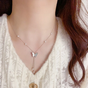 Elegant silver butterfly tassel necklace with shell wings and pearls on lace dress