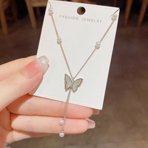 Detail of shell butterfly tassel necklace with sparkling diamonds and pearl accents