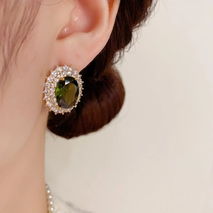 Gros plan de boucles d'oreilles ovales vert émeraude avec zircon double rangée sur un modèle
