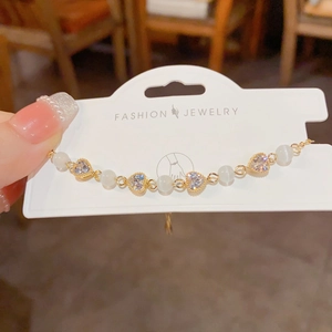 Macro detail of gold-plated heart bracelet with cat-eye beads and sparkling zircon