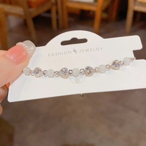 Detail view of heart-shaped zircon and cat eye stone beads on a silver chain bracelet