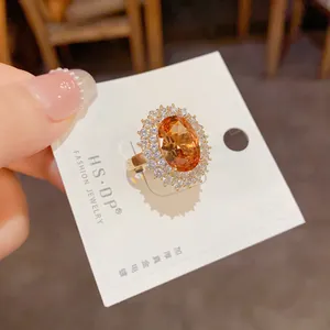 Détail macro d'une bague cocktail dorée avec grosse gemme orange et pavage de zircons
