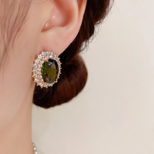 Gros plan d'une boucle d'oreille émeraude et zircon avec pavé de cristaux sur modèle