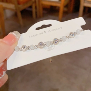 Close-up of cat eye bead and rhinestone heart bracelet on a display card
