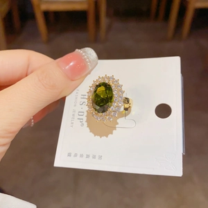 Gros plan d'une bague émeraude ovale avec double halo de zircons sur un anneau doré