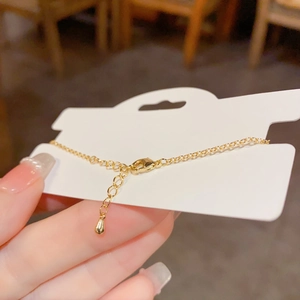 Elegant gold heart bracelet with cat-eye stone held against a warm lifestyle background
