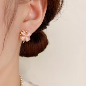 Close-up of pink cat eye stone clover stud earrings worn with a pearl necklace