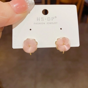 Close-up of pink five-petal flower earrings with golden beads on fashion jewelry card