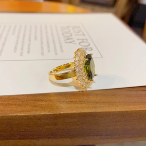 Détail d'une bague émeraude ovale avec micro-pavage de zircons sur monture dorée