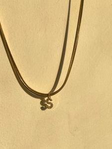 Detailed macro view of an 18k gold plated snake chain with a zircon S letter pendant