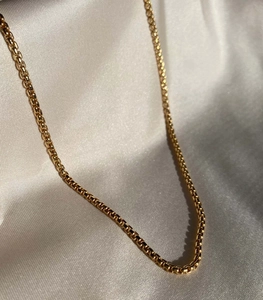 Primer plano de cadena de bolas chapada en oro de 18k sobre raso gris elegante