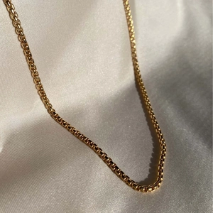 Collar de cadena veneciana chapada en oro de 18k pulido sobre elegante fondo de satén blanco