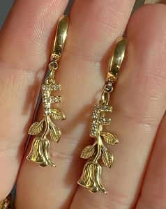 Detail von goldfarbenen Ohrringen mit F-Buchstaben-Diamanten und Vintage-Rosenanhängern
