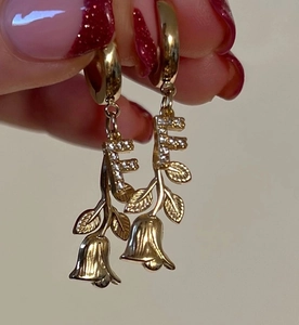 Detailansicht goldener T-Creolen mit Buchstaben F und einer Kristall-Rosenverzierung