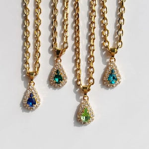 Close-up of four teardrop pendants in blue and green with 18k gold plated chains
