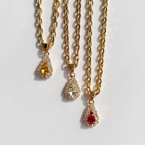 Detailed macro view of pear-cut crystal teardrop pendants with gold plated chain
