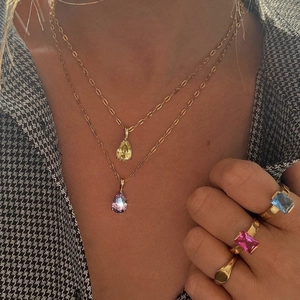 Detail of layered 18k gold necklaces and gemstone rings on a fashion model