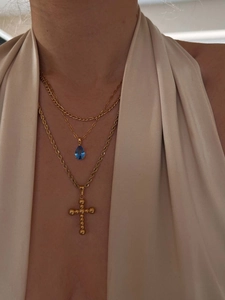 Close-up of triple-layered 18k gold-plated necklaces with blue teardrop stone and cross