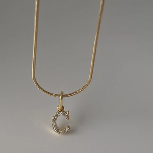 Detail der 18k vergoldeten Schlangenkette mit einem funkelnden Buchstaben C Anhänger