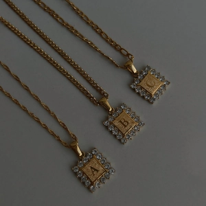 Detail van drie 18k vergulde letterhangers A B C met sprankelende strassteentjes
