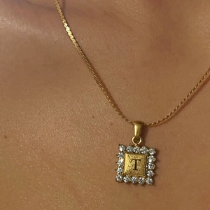 Detail van 18k vergulde vierkante hanger met letter T en fonkelende kristallen