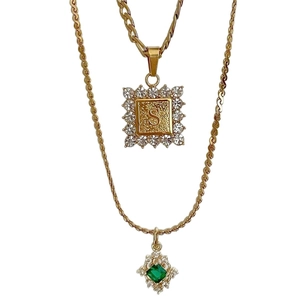 Gouden multi-ketting met letter S hanger en bedeltje met groene edelsteen
